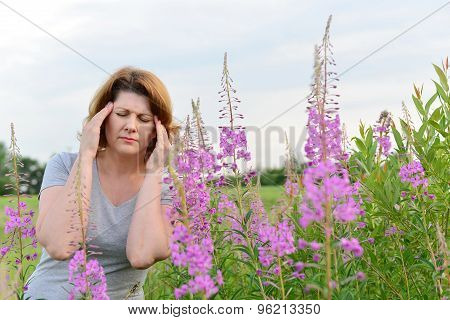 Portrait of  woman with headache near willow-herb in the field