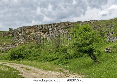 General view toward sedimentary rock with cave in the field