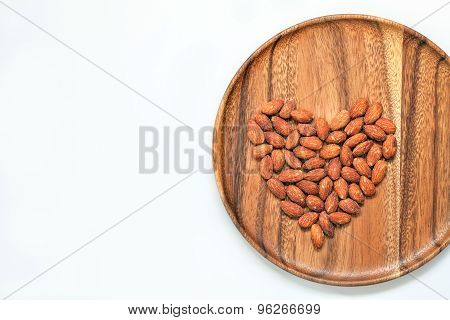 Salted & roasted almonds on wooden dish and white background