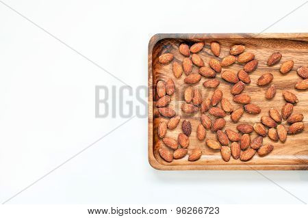Salted & roasted almonds on wooden saucer and white background