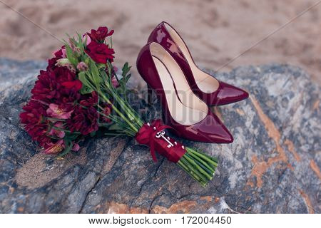 Red women's shoes with red wedding bouquet close-up