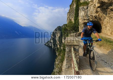 View of cyclist riding mountain bike on trail Sentiero Ponale in Dolomites,Tre Cime di Laverado, South Tirol, Italy