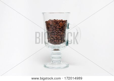 Transparent cup with coffee beans on white background.
