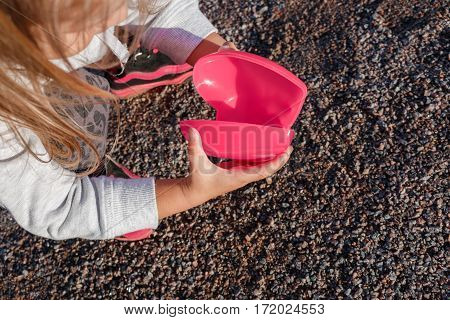 Little Girl Playing With A Red Plastic Heart. She Holds It In Her Hands