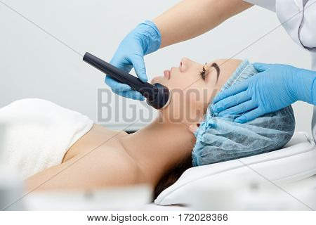 Hypersonic Phonophoresis. Model and doctor. Cosmetological clinic, procedure. Profile, close-up Healthcare clinic cosmetology