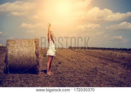 Happy woman with wheat bale in summmer sunset