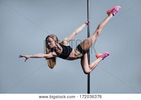 Young slim pole dance woman on blue background
