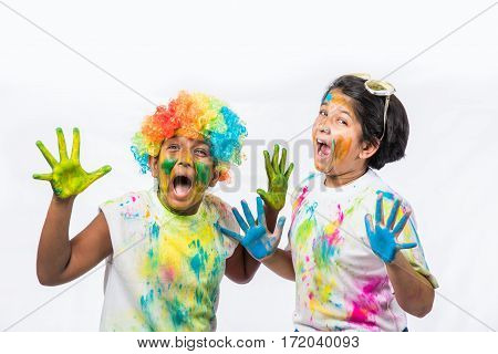 indian siblings playing colours, kids celebrating holi with gulal and pichkari, isolated over white