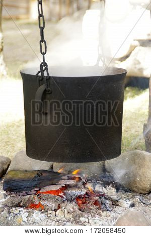 Old black pot on fireplace, chain, stones
