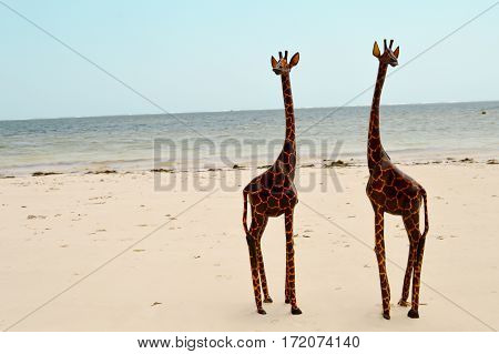 Couple of giraffes carving exposed on the white sandy beach of Bamburi in Mombasa Kenya