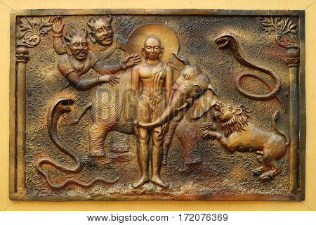 KOLKATA,INDIA - FEBRUARY 09: The Yaksa Sulapani tries to harass Bhagavan Mahavira while absorbed in deep meditation, bass relief on the wall of Jain Temple (also called Parshwanath Temple) in Kolkata.
