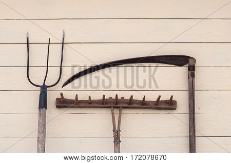 Old hand tools for agriculture on the background wall from boards