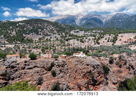 White church and ancient ruins at cliff of Aradena Gorge, Crete island, Greece