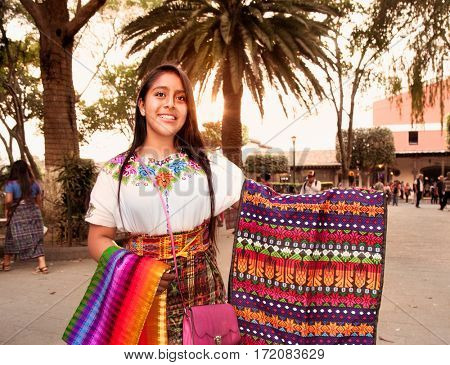 ANTIGUA, GUATEMALA-DEC 26, 2015: : Beautiful guatamalian girl selling traditional colorful fabric at the street in Antigua on Dec 26, 2015, Guatemala.