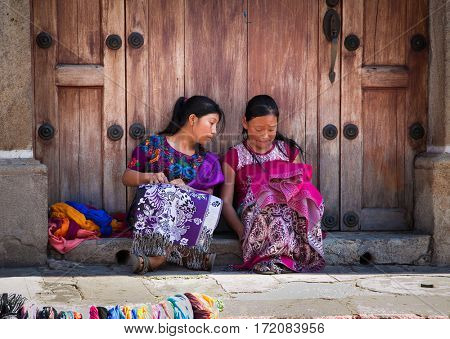 ANTIGUA, GUATEMALA-DEC 26, 2015: : Guatamalian girls selling traditional  colorful fabric and goods at the street in Antigua, on Dec 26, 2015, Guatemala.