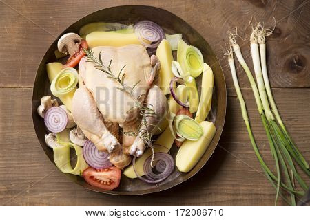 Preparation for roasting chicken with herbs and vegetables in a copper pot
