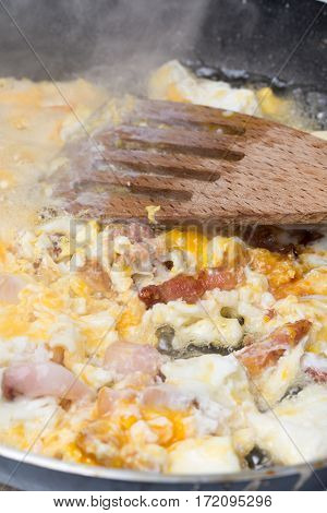 Frying eggs with sliced bacon in the hot oil.