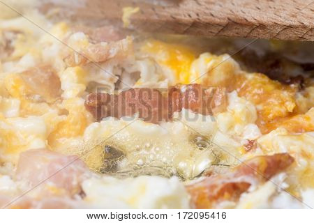 Frying eggs with sliced bacon in the hot oil.