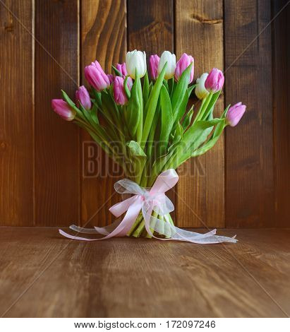 beautiful bouquet with pink and white tulips standing on wooden background