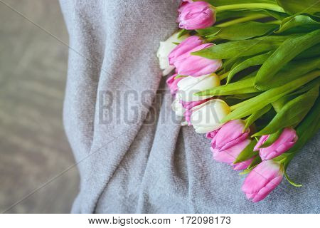 Bouquet of pink and white tulips with pink ribbon on gray blanket