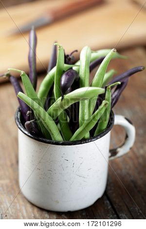 Green and purple string bean in the vintage mug