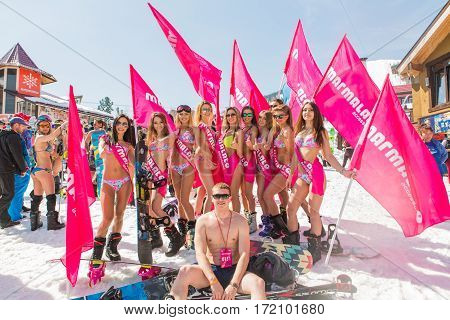 Group Of Young Happy Pretty Women On A Snowboard In Colorful Bikini With Flags.