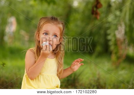 Nice little girl eating candy candy during a walk in the summer park. Summer vacation. Outdoor Activities.