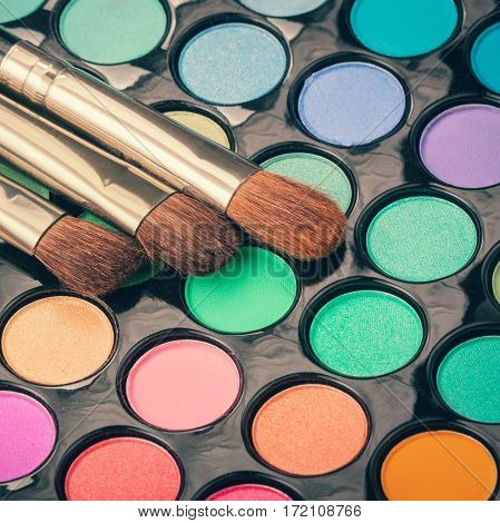 Set of makeup brushes on colorful eyeshadow palette