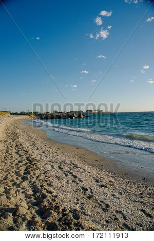 A sandy beach with tons of shells and crystal blue water - Vertical