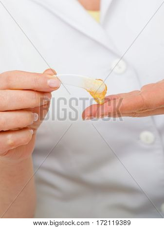 Woman Applying Cream On Hand Using Spatula