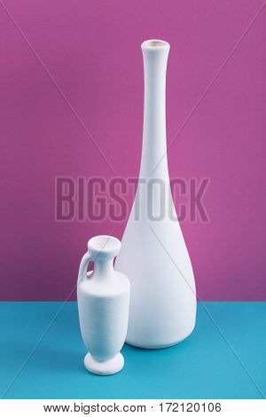 Still-life with white vases on a colored background