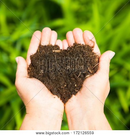 Hands Holding An Earth Heart On Natural Green Background. Ecology Concept