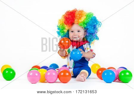 Children clown with a red nose multicolored wig in with balls. On a white background.