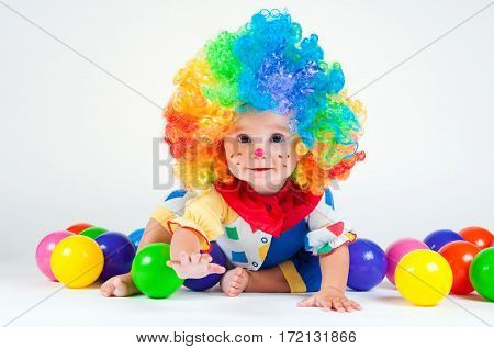 Children clown with a red nose multicolored wig in with balls. On a white background.