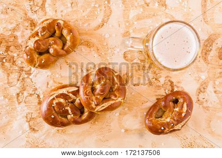 Several salty cooked pretzel and lager beer seen from above over the greaseproof paper