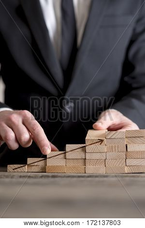 Vertical close-up of businessman building career ladder stairs or growing graph concept of wooden domino bricks with upcoming arrow.