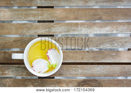 Petals of Eustoma russellianum flower in tea cup on wooden table