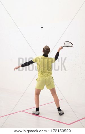 back view of squash player hitting a ball in a squash court. Squash player in action. Man playing match of squash