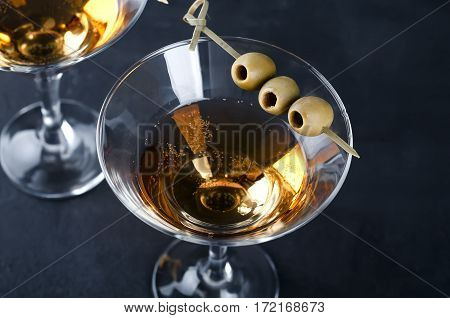Martini glass and olives isolated on black concrete background