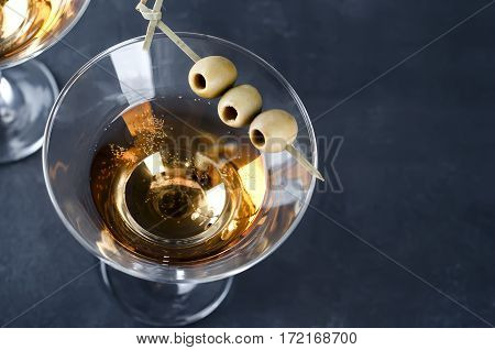 Martini glass and olives isolated on black concrete background