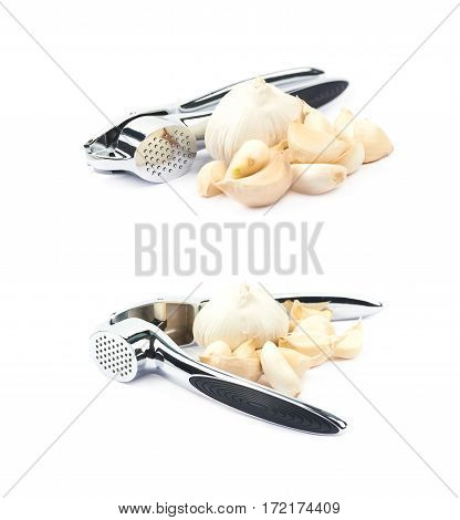 Metal garlic press utensil next to a pile of fresh cloves isolated over the white background, set of two different foreshortenings
