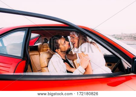 Young Girl In White Dress And Man Sitting On The Front Seat Of The Red Ferrari