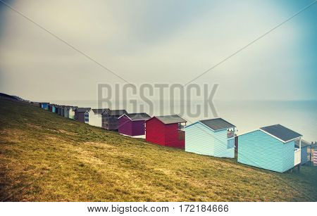 Row of colored beach huts with stormy blue sky on the beach of Tankerton near Whitstable in Kent, UK