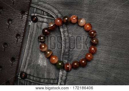 Bracelet on the arm on the background of jeans, top view