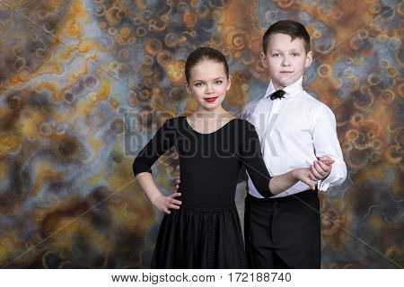 Young boy and girl are dancing on the studio wall background