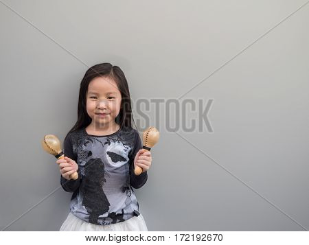 Little Asian Child Play The Maracas, Gray Background