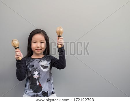 Little Asian Child Play The Maracas, Gray Background