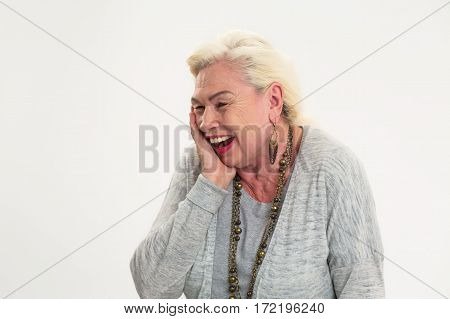 Isolated elderly lady laughing. Cheerful woman touching her face. Great sense of humour.