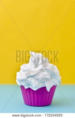 closeup of a pink plastic cup full of a white ice cream on a blue and yellow background