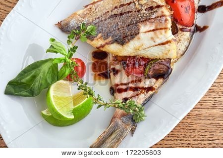 Fried Fish Dorado Garnished on Sliced Pumpkin with Basil Leaf and Sauce